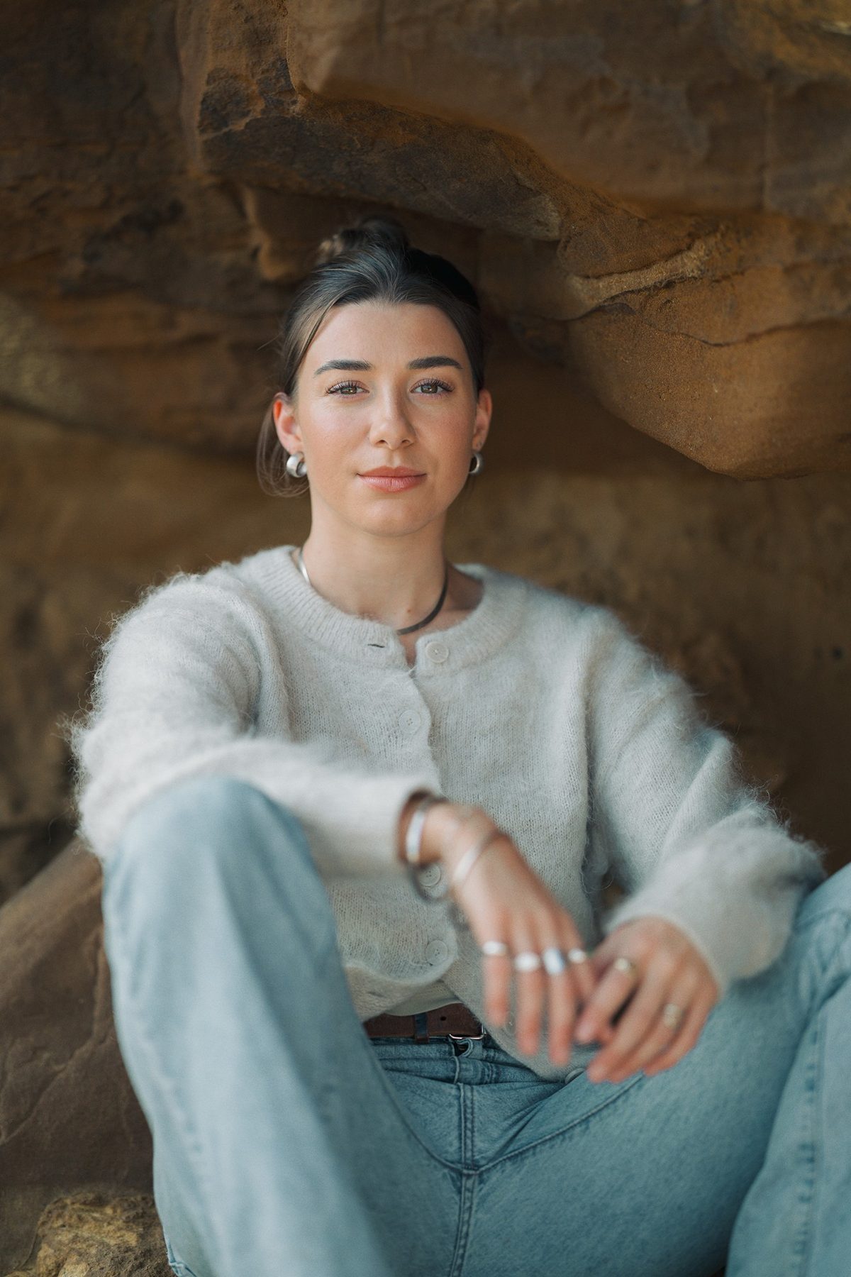 Charli Grace sitting in a sandstone rock cave