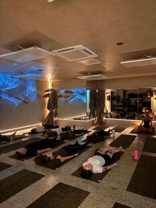 Students resting in savasana in a candlelit studio